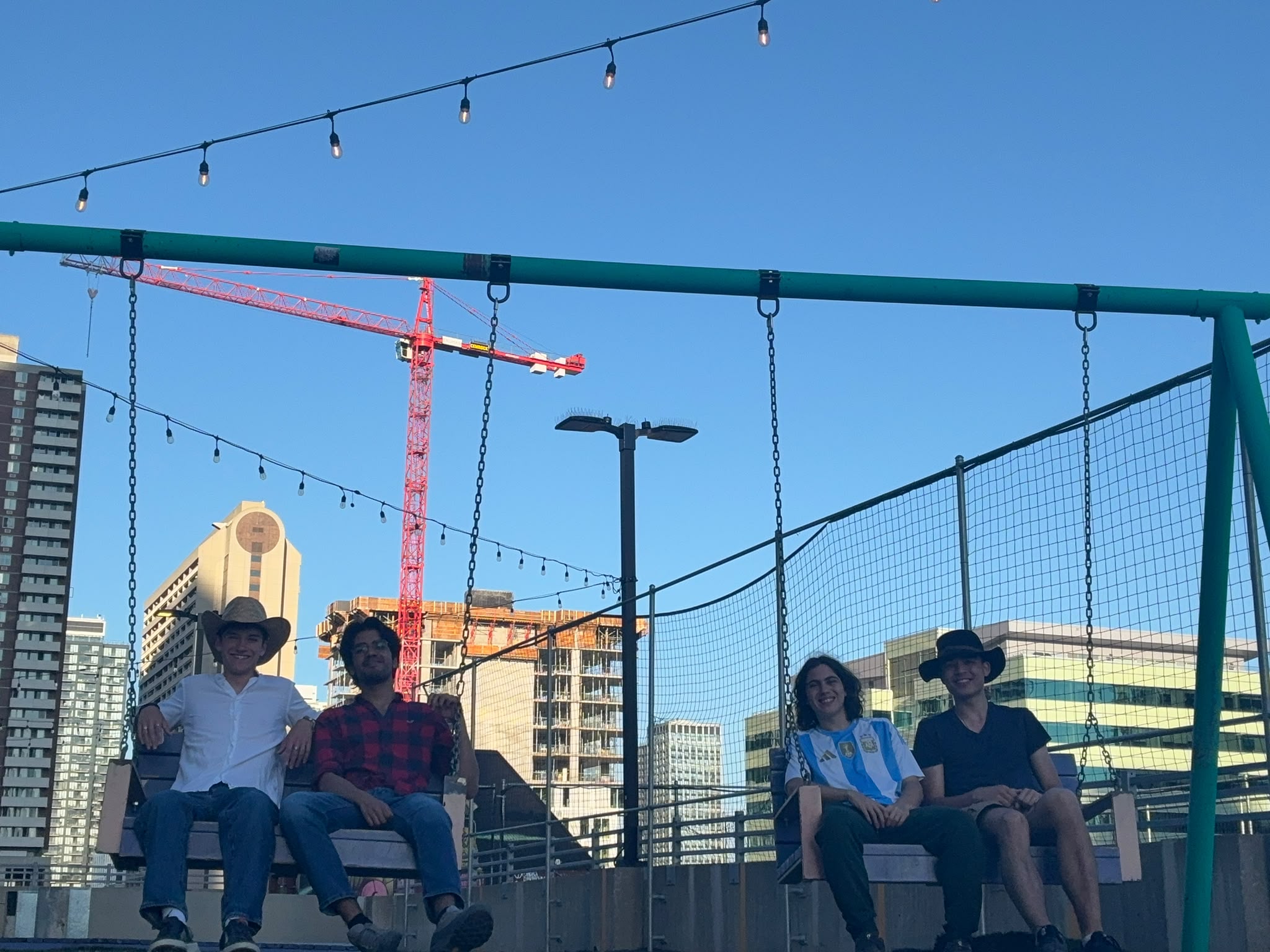 Friends on rooftop swings above downtown